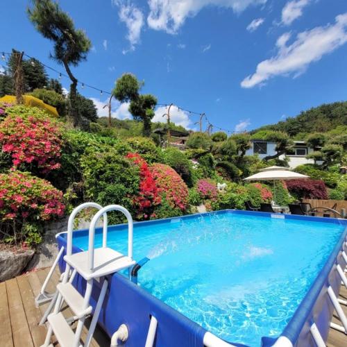a swimming pool with two chairs and flowers at Gapyeong Petmily Dog Pension in Gapyeong