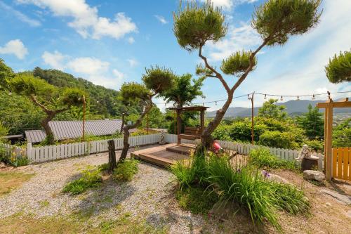 a garden with a wooden bench and a tree at Gapyeong Petmily Dog Pension in Gapyeong