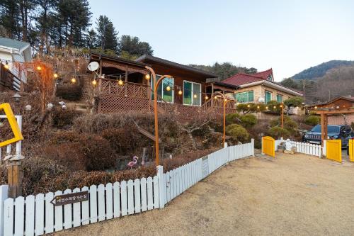 a house with a white fence in front of a yard at Gapyeong Petmily Dog Pension in Gapyeong