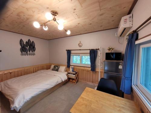 a bedroom with a bed and a desk and a window at Gapyeong Petmily Dog Pension in Gapyeong