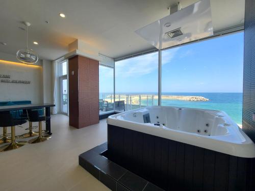 a large bath tub in a room with a view of the ocean at Sokcho 828 Spa Pension in Sajin