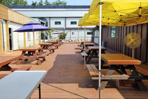 a row of picnic tables with umbrellas on a deck at Jeongpo Pension in Taean