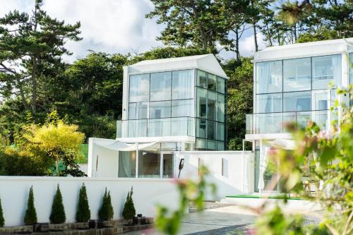a glass house with a white fence and trees at Ulsan Nasa Pool Villa in Ulsan