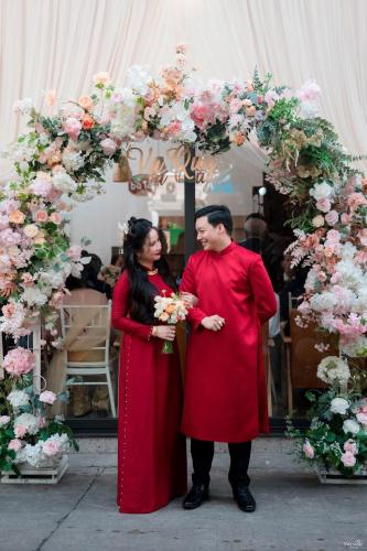 a man and a woman standing under an arch of flowers at BA TAM VU SUA Homestay in Ho Chi Minh City