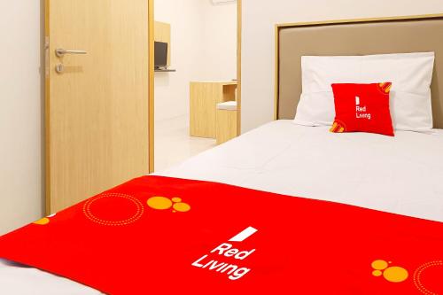 a red and white bed with a red linux blanket on it at RedLiving Star Apartemen Semarang - UMAKU Lantai 16 in Jomblang