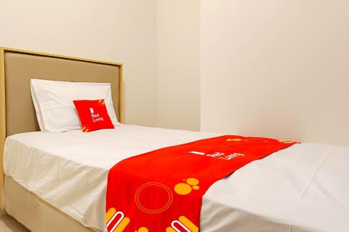 a bed with a red blanket on top of it at RedLiving Star Apartemen Semarang - UMAKU Lantai 16 in Jomblang