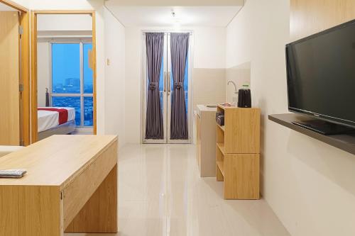 a living room with a television and a bedroom at RedLiving Star Apartemen Semarang - UMAKU Lantai 16 in Jomblang