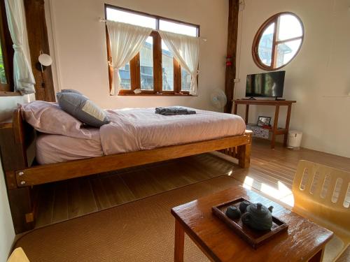 a bedroom with a bed and a table and a window at บ้านมิยากาวา in Chiang Mai