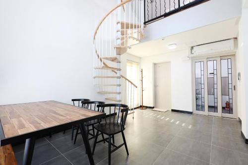 a dining room with a table and chairs and a spiral staircase at Samcheok santiago pension in Samcheok