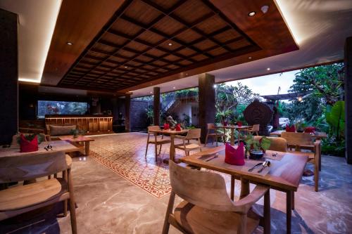 a restaurant with wooden tables and chairs and a patio at Emana Akatara in Ubud