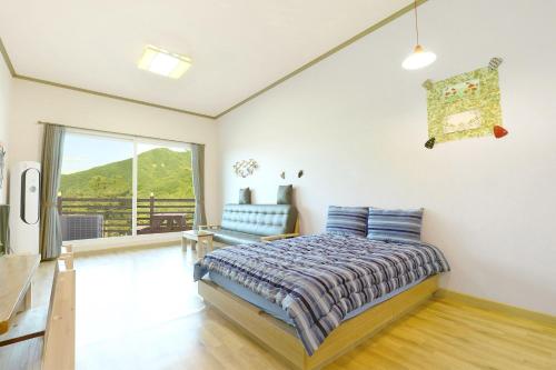 a bedroom with a bed and a chair and a window at Gapyeong Ttongkkodeuruisuda Pension in Oebang-ni