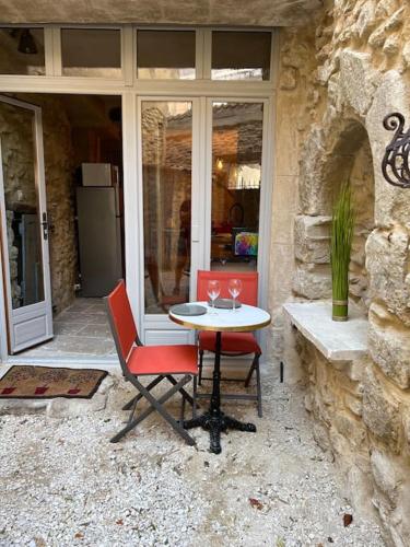 une table et des chaises assises devant un bâtiment dans l'établissement Grand studio de charme dans une bâtisse du XVII, à LʼIsle-sur-la-Sorgue
