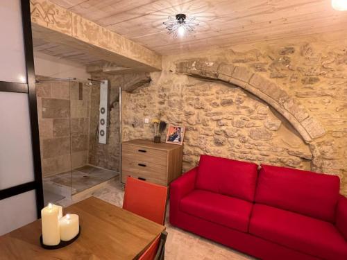 - un salon avec un canapé rouge et un mur en pierre dans l'établissement Grand studio de charme dans une bâtisse du XVII, à LʼIsle-sur-la-Sorgue