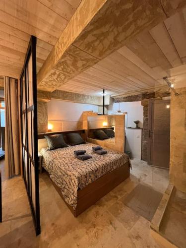 une chambre avec un grand lit dans une pièce dans l'établissement Grand studio de charme dans une bâtisse du XVII, à LʼIsle-sur-la-Sorgue