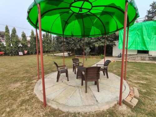 a group of chairs and a table under a green umbrella at Nature Homestay in Varanasi