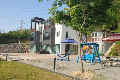 a playground with a blue swing and a tree at Haneulbada Pension in Seosan