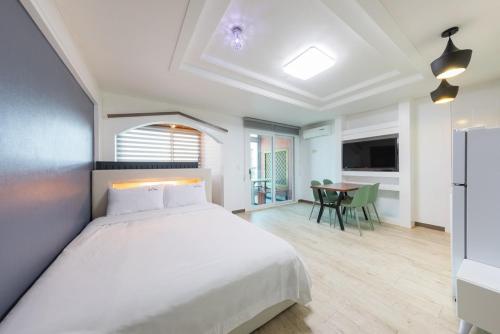 a bedroom with a large white bed and a table at Gyeongju Cookie and Jelly Pension in Gyeongju