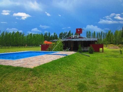 a swimming pool in a field with a building at Cabaña La Tranquera in San Rafael