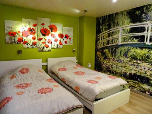 two beds in a room with paintings on the wall at Datcha Bourguignonne, Chambres & Gîte in Maconge