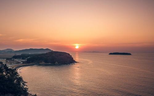 a sunset over a body of water with an island at Byeonsan Barahan Pension in Buan