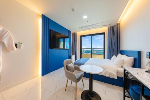 a hotel room with a bed and a table with a chair at Donghae Sunshine in Mukho-dong