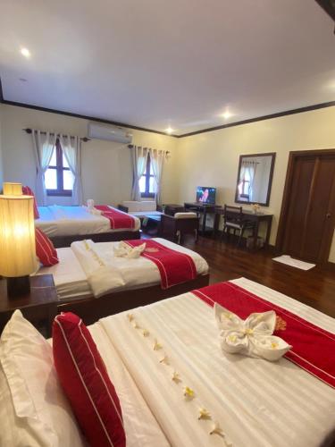 a hotel room with three beds with red and white sheets at Luang Prabang Residence & Travel in Luang Prabang