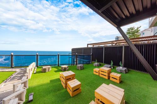 a patio with tables and chairs on a balcony with the ocean at Samcheok Laon Spa Pension in Samcheok