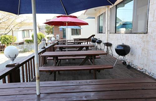 a group of picnic tables with umbrellas on a deck at Cheongsachorong Pension Gapyeong in Taean