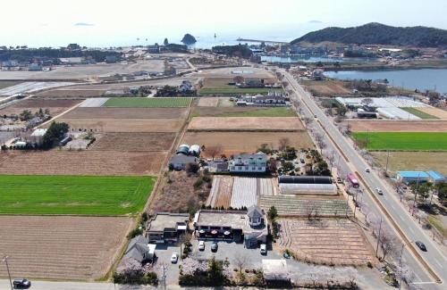 an aerial view of a farm with a road and a field at Cheongsachorong Pension Gapyeong in Taean