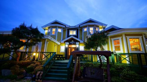 a large yellow house with stairs in front of it at Buan lemon terrace pension in Buan