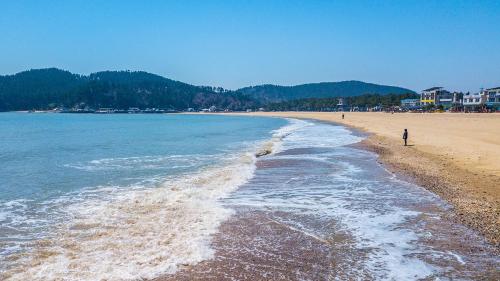 a beach with a person walking on the shore at Taean The sea side Pension in Tohwang-ni