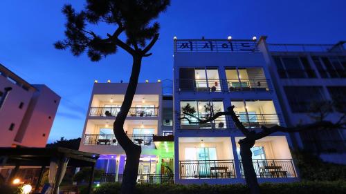a white building with a tree in front of it at Taean The sea side Pension in Tohwang-ni