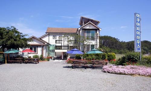 Un edificio con bancos y sombrillas delante. en Aquapia House, en Taean