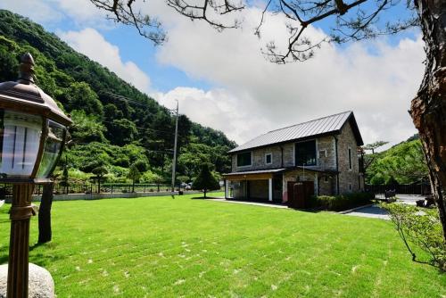 a house with a green lawn in front of a building at Gapyeong La Vie En Rose Private Pension in Gapyeong