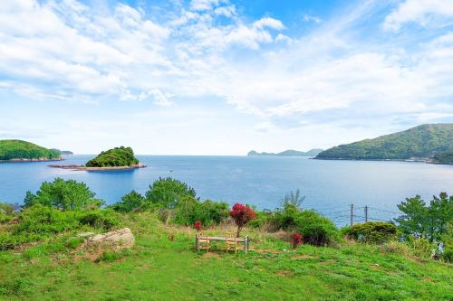 a bench sitting on top of a hill next to a body of water at Geoje Badaga Joa Pension in Geoje 