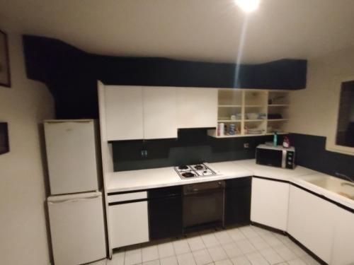 una cucina con mobili bianchi e un frigorifero di Chambre Pessac proche rocade aéroport a Pessac