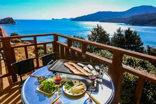 a table with food on a balcony with a view of the ocean at Geoje Badaga Joa Pension in Geoje 