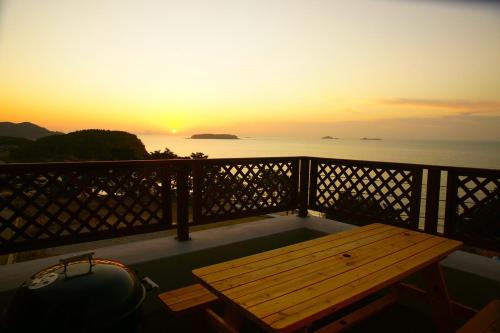 a wooden bench on a balcony with a sunset at Buan baramyisogsagimA pensyeon in Buan