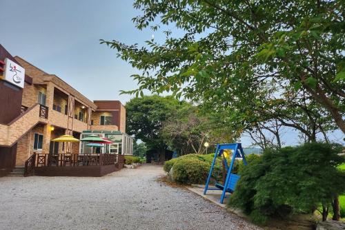 a playground in front of a building next to a building at Anmyeondo Noeul Shimteo Pension in Chŏkkae