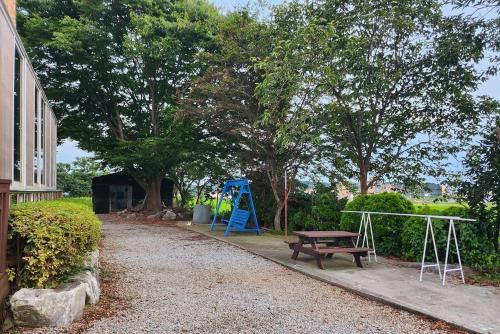 a playground with a bench and a blue swing at Anmyeondo Noeul Shimteo Pension in Chŏkkae