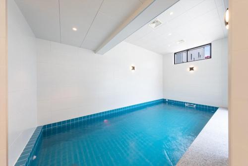 a swimming pool in a white room with blue water at Gangneung Gyeongpo 345 Pool Villa in Kyŏngp'o-mal