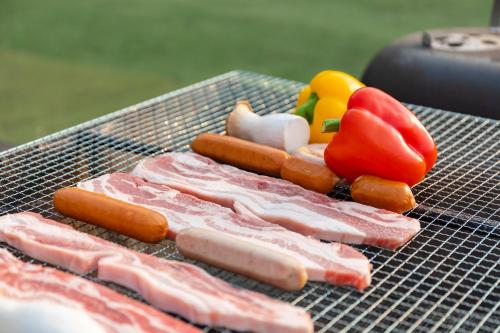 a bunch of hot dogs and vegetables on a grill at Free Time Pension Gapyeong in Gapyeong