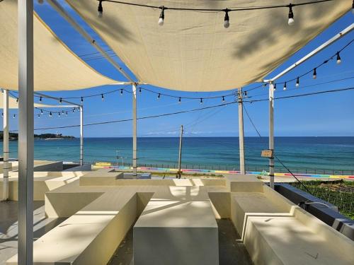 a group of benches under a tent with a view of the ocean at Goseong Stay Naru in Goseong