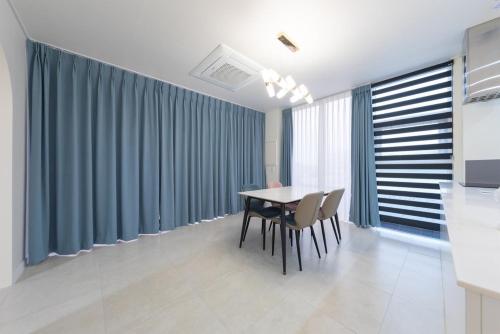 a dining room with a table and chairs and blue curtains at Gangneung Heonhwa-ro Pension in Gangneung