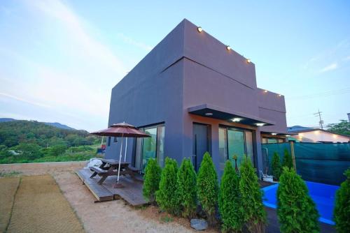 a small house with a table and an umbrella at Byeonsanbando The Forest Pension in Buan