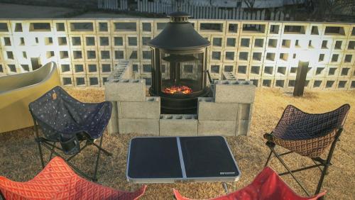 a fire pit with chairs and a table and a grill at Gangneung Boni Stay in Ŭmji-mal