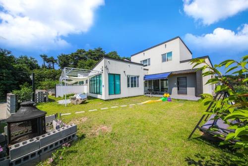 a large yard with a white house and a building at Gangneung Boni Stay in Ŭmji-mal