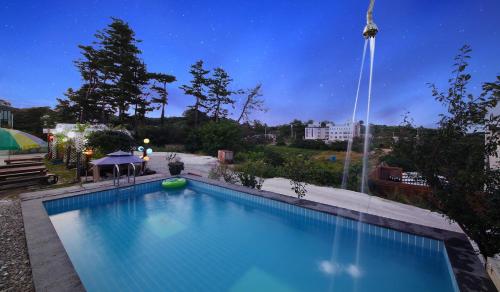 a large blue swimming pool at night at Gangreung rosepension in Yŏngjin 2-ri