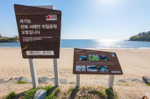 a sign on the beach with the ocean in the background at Buan Sonamuae Geolin Noeul Pension in Buan