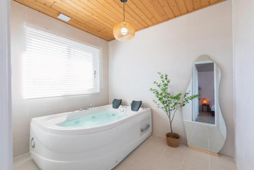 a white bathroom with a tub and a window at Gyeongju Insta Spa Pension Spa, Individual BBQ in Gyeongju